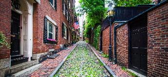 A mossy cobblestone street lined with red-brick houses in Beacon Hill, Boston